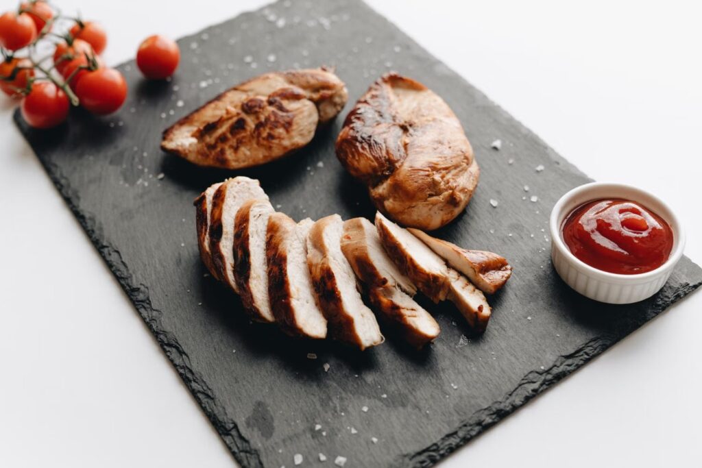 Peito de frango grelhado fatiado com tomate sobre tábua de ardósia